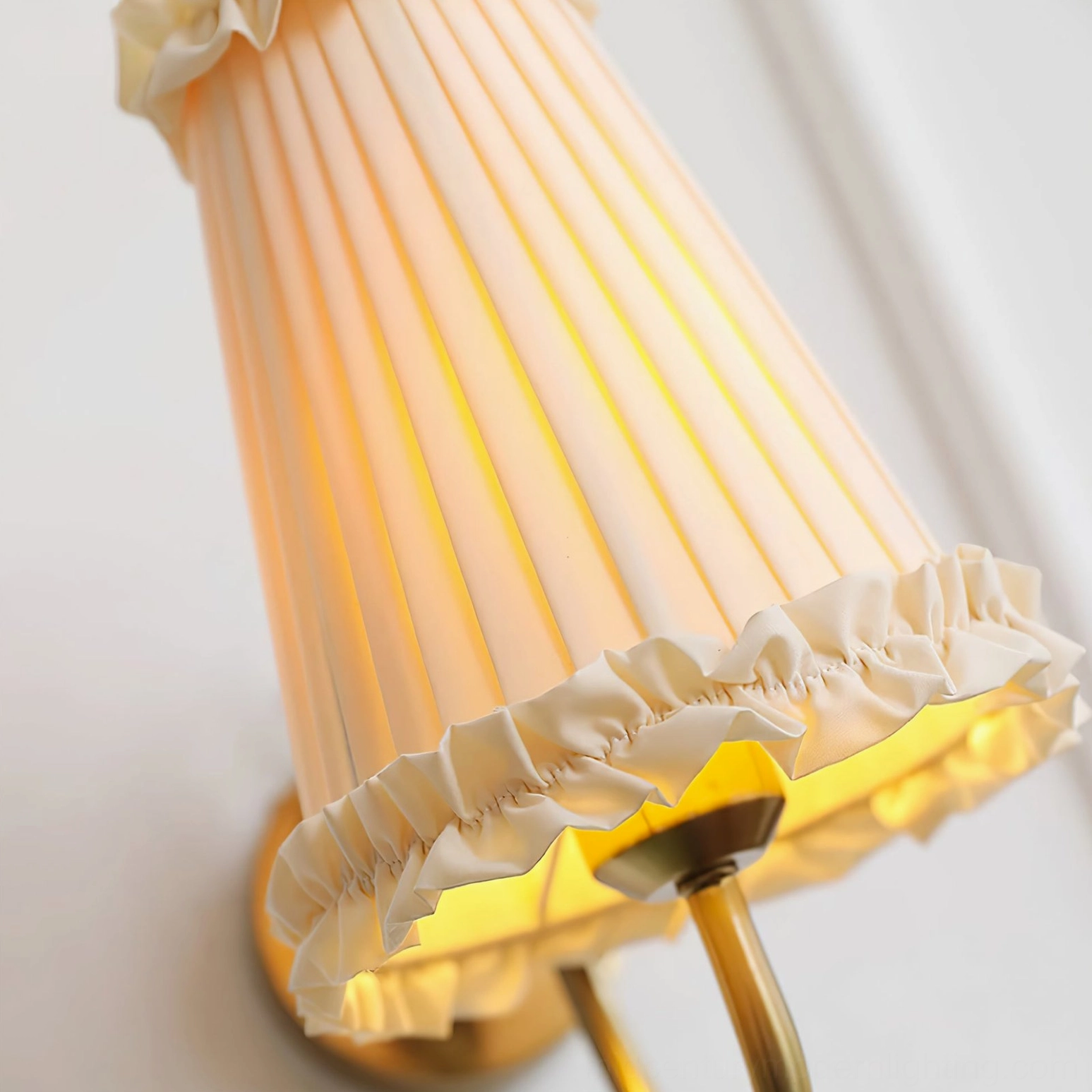 Close-up detail of pleated fabric shade with ruffled trim and warm glowing light from inside