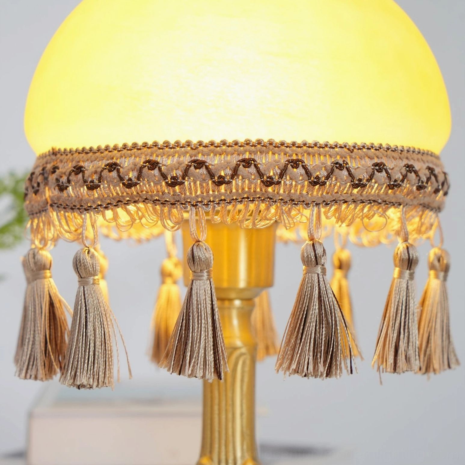Close-up of hanging beige linen tassels and warm glowing lamp interior