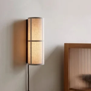 Minimalist bedroom wall sconce with fabric cylinder shade mounted on neutral wall at eye level
