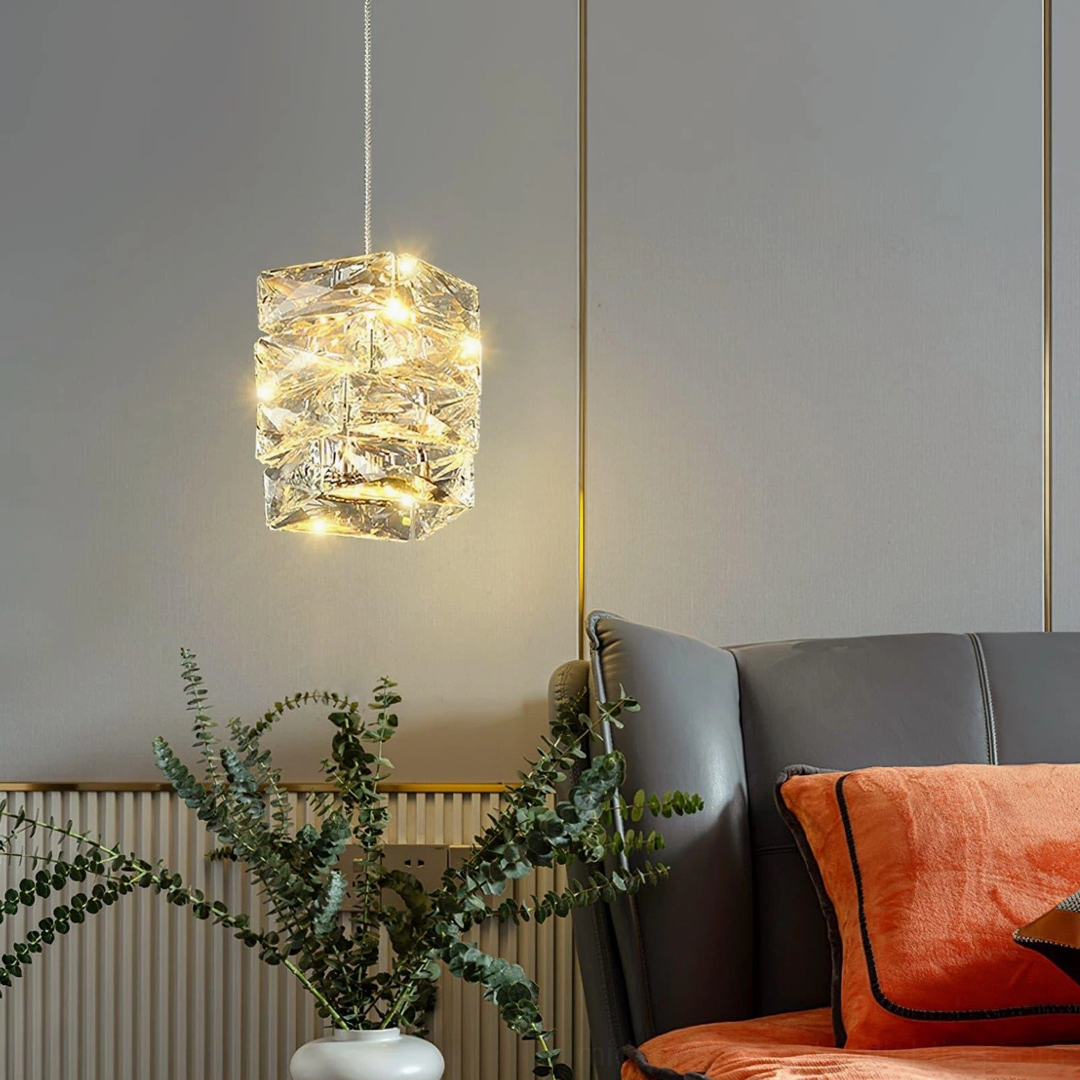 Single faceted crystal cylinder pendant lamp suspended in modern living room lounge area with home decor accent