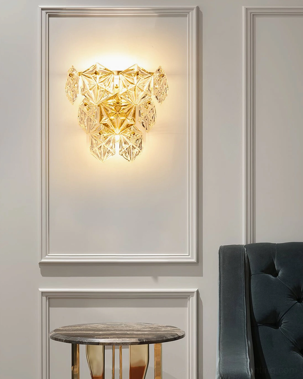 Faceted crystal wall sconce with polished gold finish mounted in modern interior space