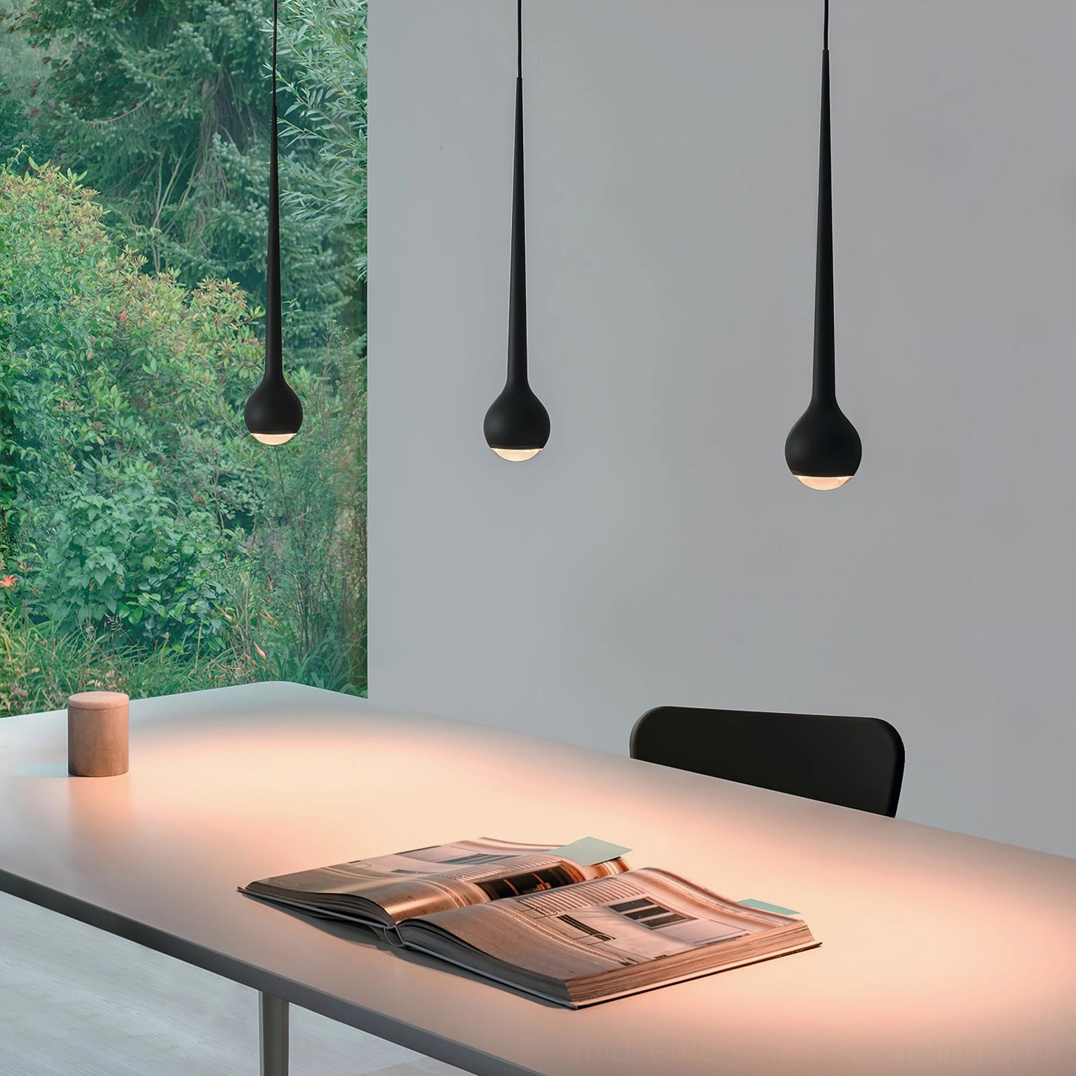 Modern teardrop pendant lamp in black providing warm downlighting over contemporary dining desk