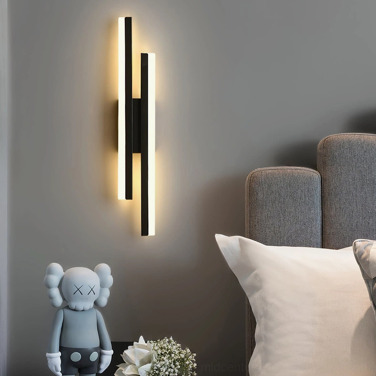 Black Fallon wall sconce mounted above modern bed with warm ambient lighting in contemporary bedroom