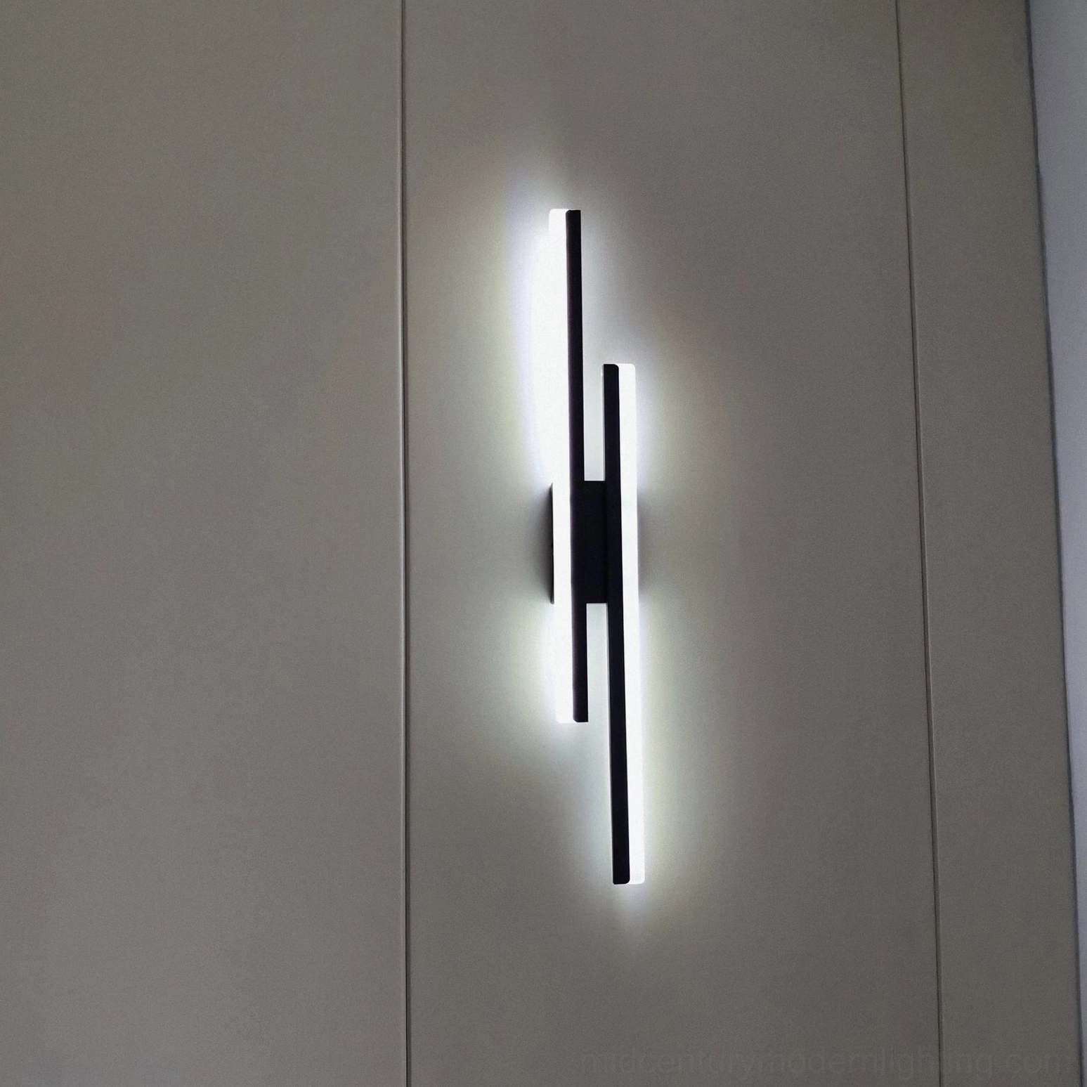 Black matte finish Fallon wall lamp with cool white LED lighting against grey wall