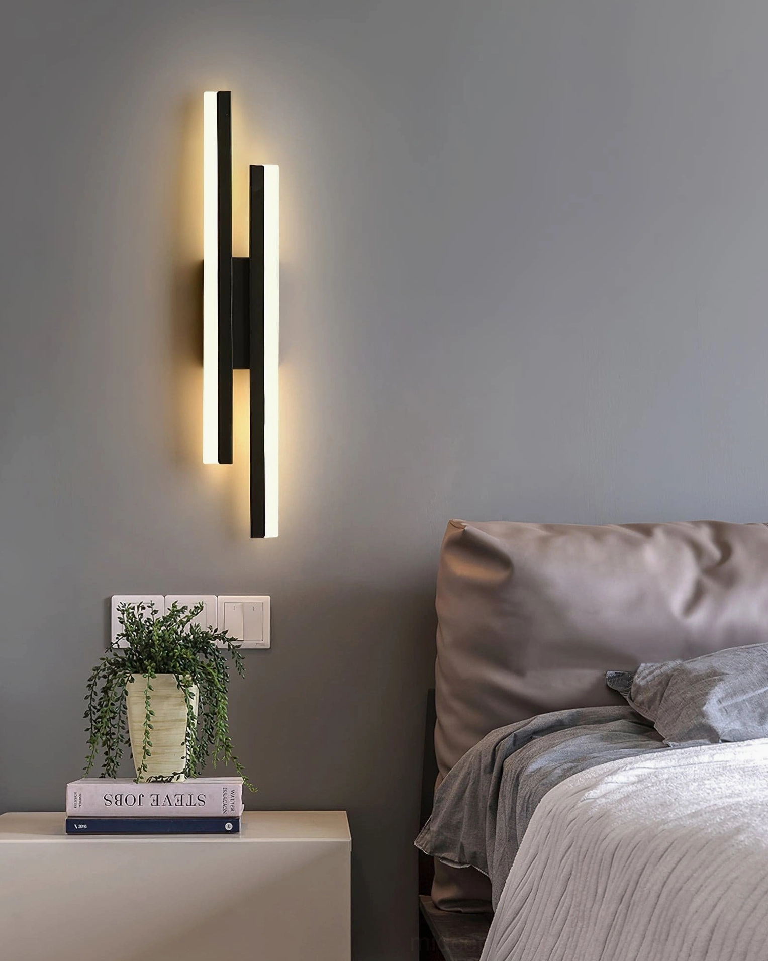 Matte black geometric wall lamp in modern bedroom interior with neutral bedding and contemporary decor