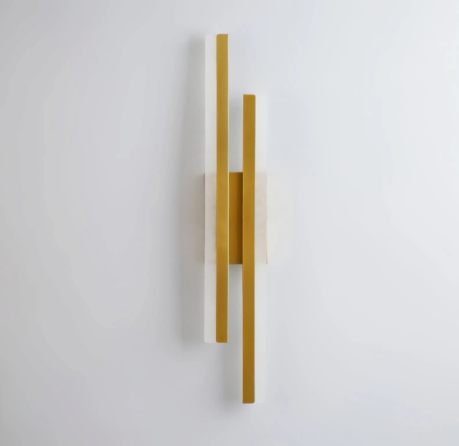 Fallon geometric wall sconce mounted on off-white wall featuring warm metal finish and modern design