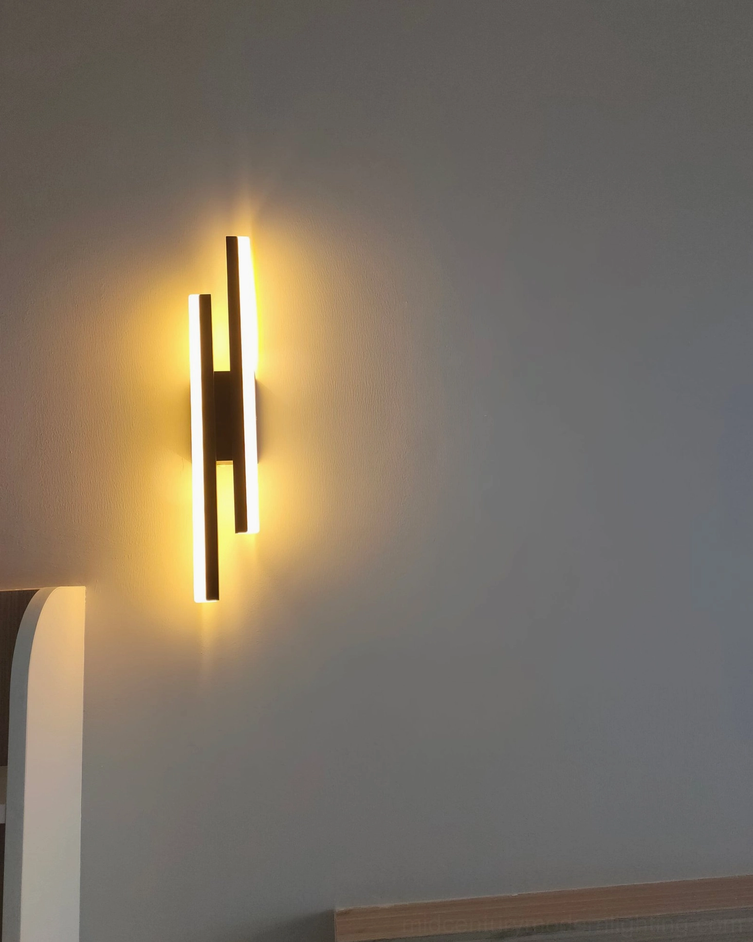 Low angle view of Fallon wall sconce in warm ambient lighting within modern bedroom setting