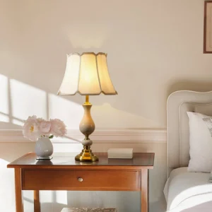 Fangio table lamp styled on wooden nightstand in bedroom with decorative vase and books