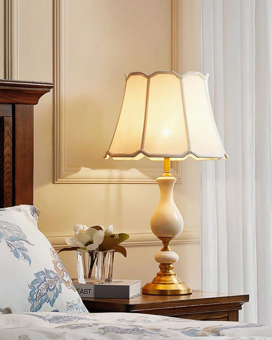 Table lamp on wooden nightstand beside upholstered bed with flower arrangement decor