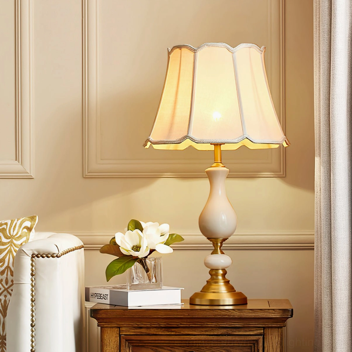 Ceramic table lamp positioned on dark round side table with framed artwork wall backdrop