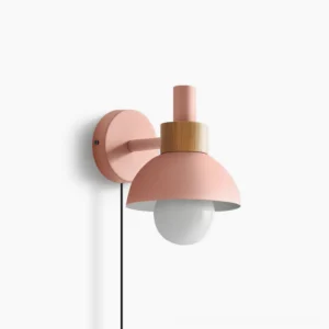 Fanta plug-in wall sconce in pink finish with natural wood detail, front three-quarter view on studio backdrop