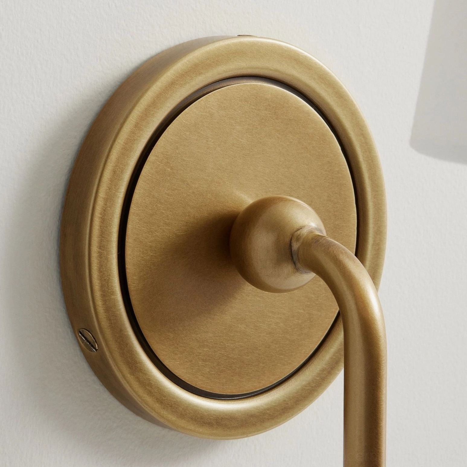 Brushed brass round backplate and mounting hardware detail of Farlane wall sconce