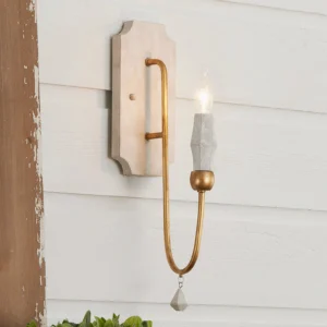 Lit candle wall lamp with curved bronze arm, crystal pendant, and faceted bulb sleeve mounted on farmhouse shiplap