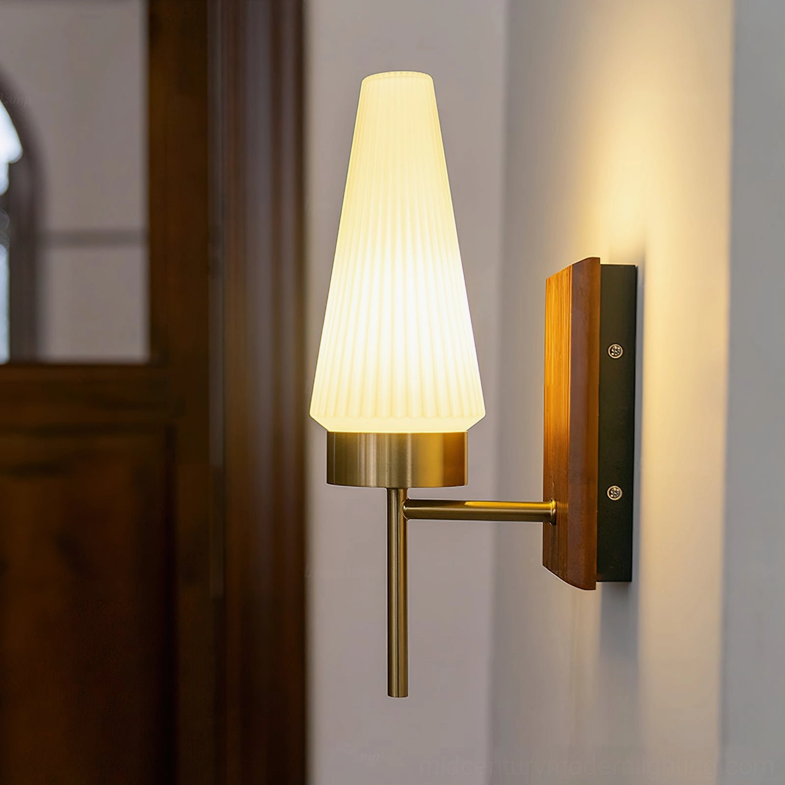 Illuminated Farrell sconce with warm ambient lighting and polished brass finish in residential entryway