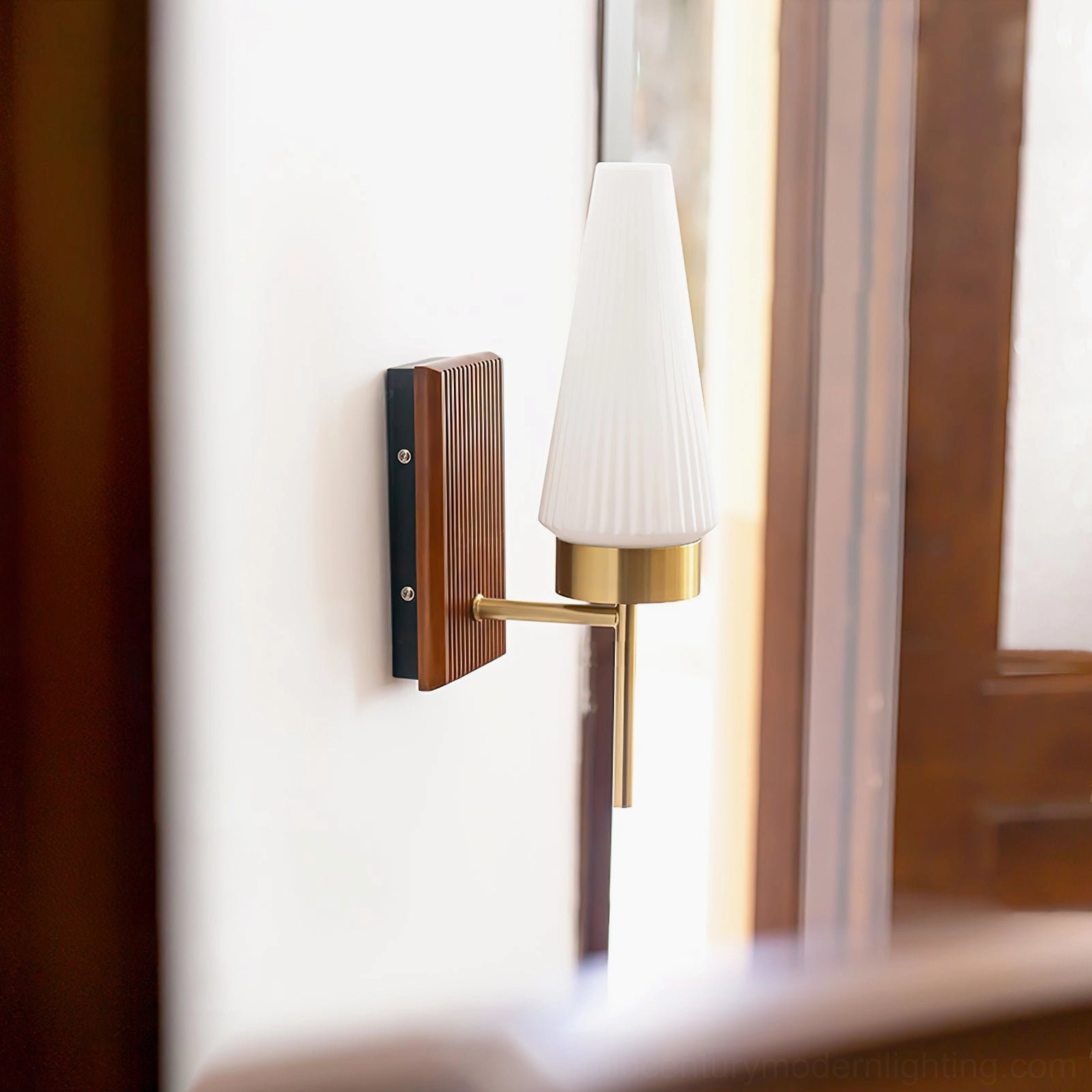 Farrell wall light side angle detail showing tapered fluted glass shade and brass metal arm in hallway setting