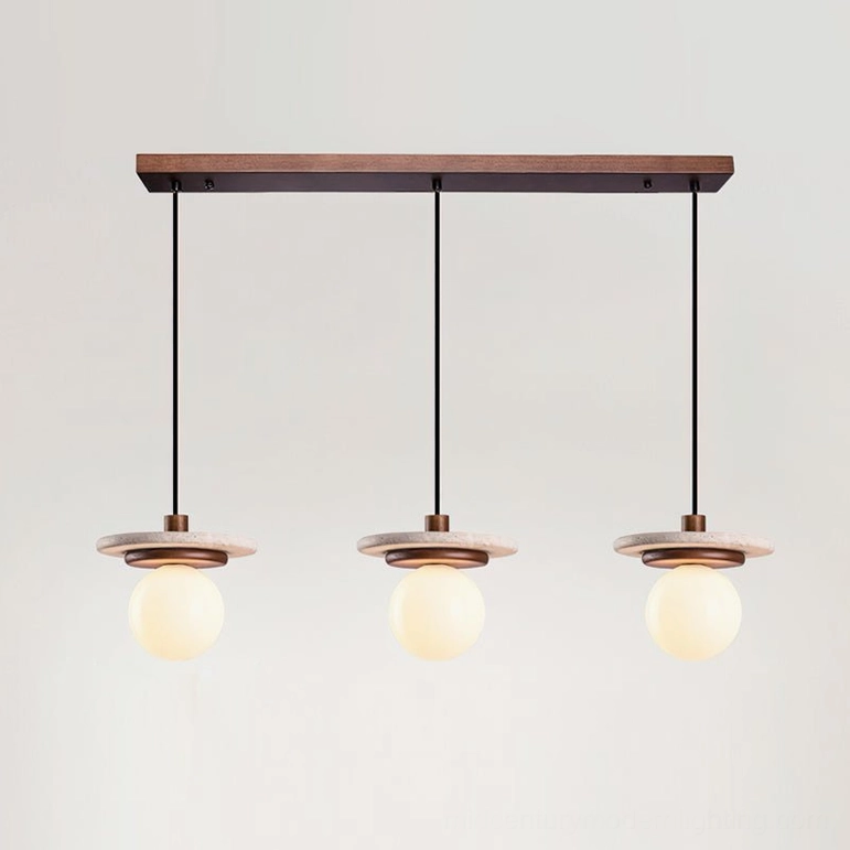 Three travertine pendant lights on linear canopy spanning kitchen island in contemporary home