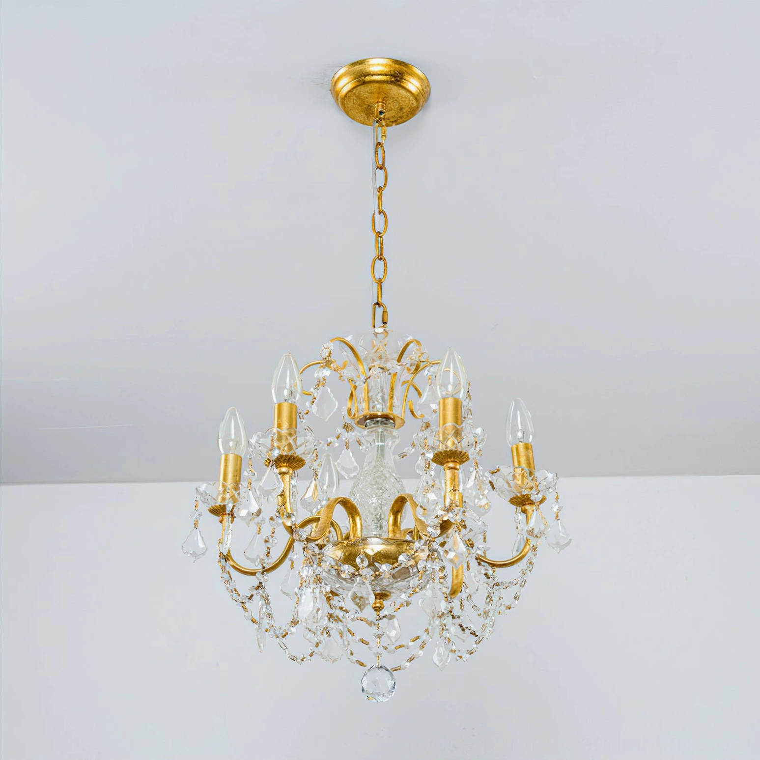 Compact Fauna crystal chandelier with gold hardware illuminated on white background, showing mid-century modern aesthetic