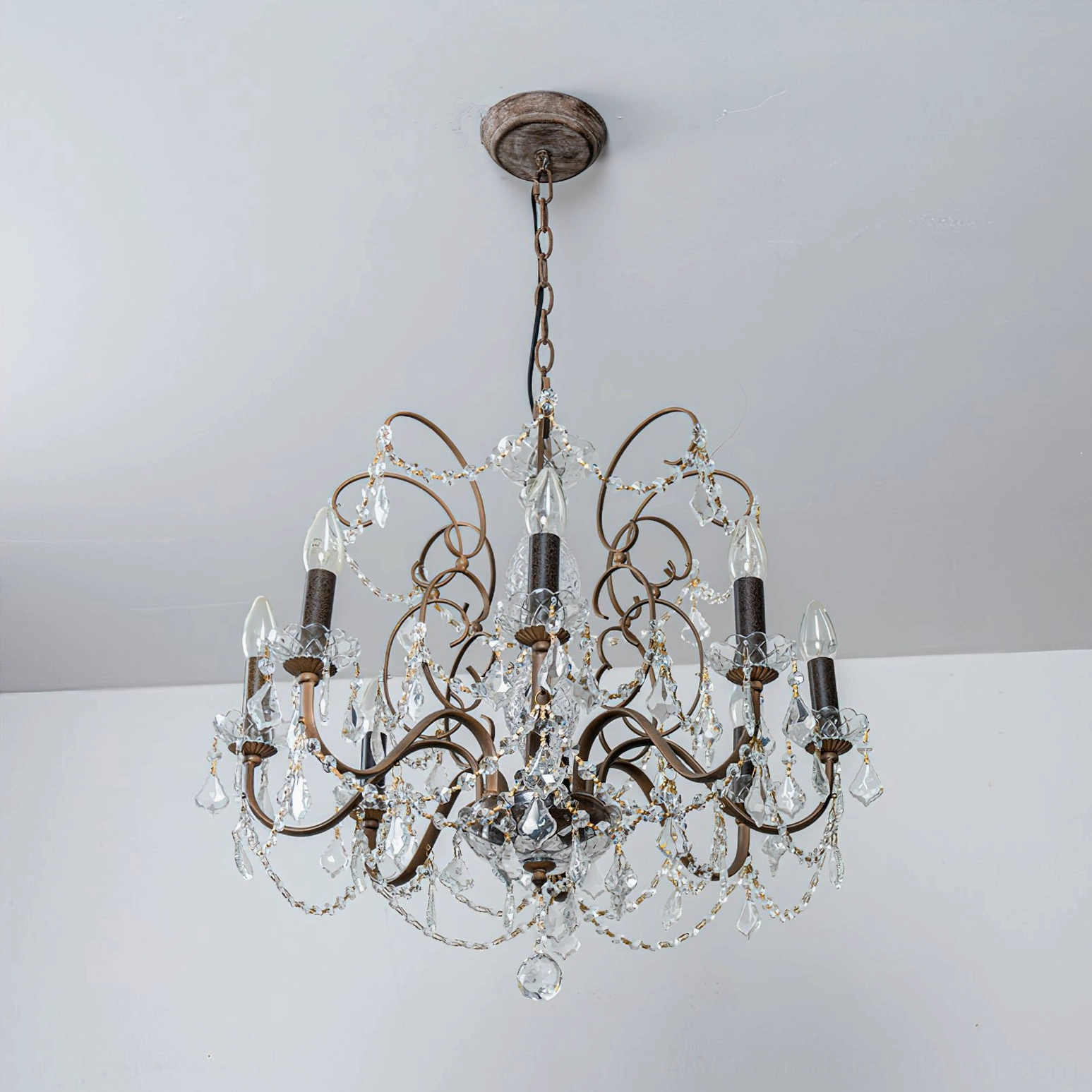Rustic rust-colored Fauna crystal chandelier with vintage bronze tones mounted indoors, creating warm atmospheric lighting