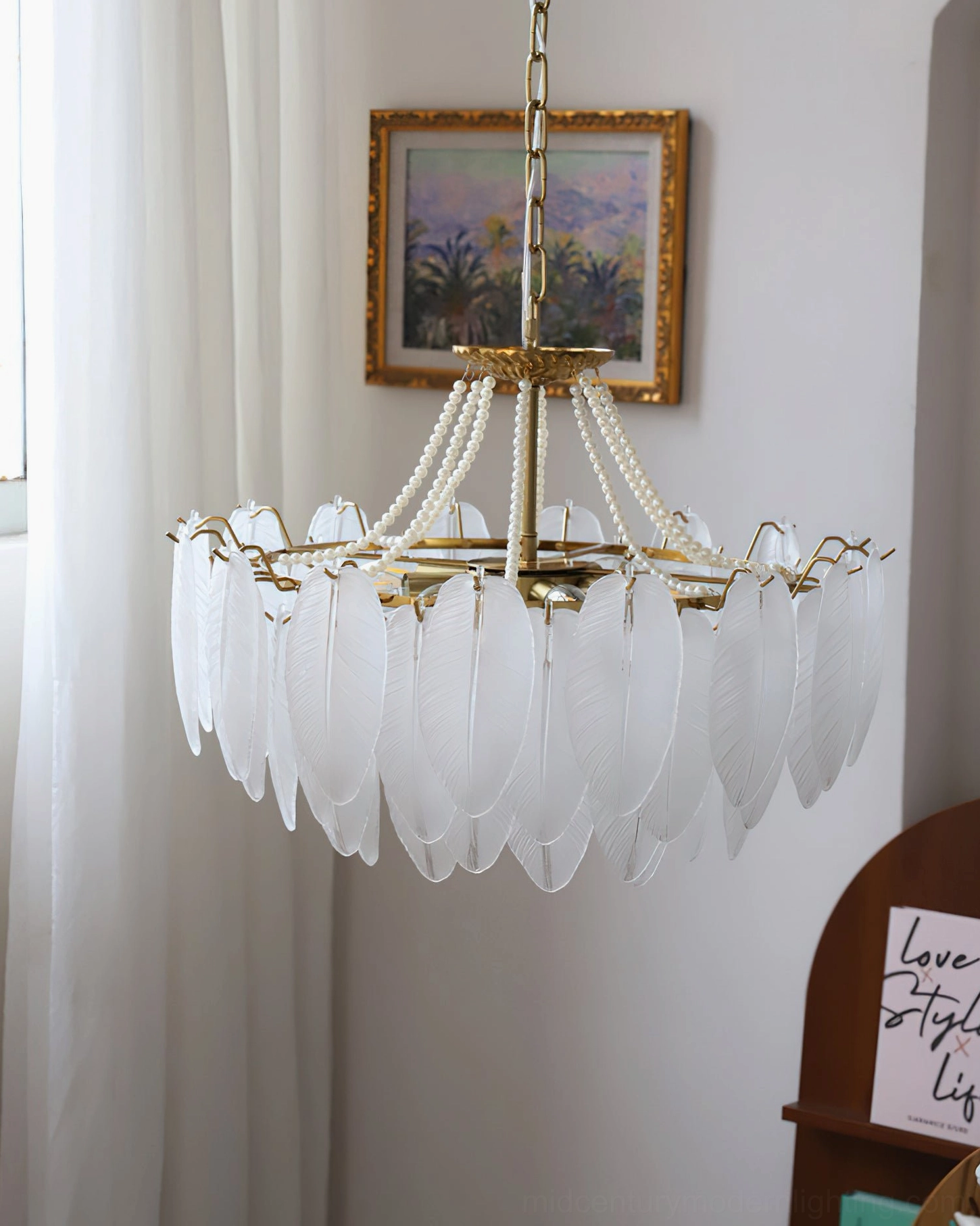Feathered glass chandelier installed above dining table creating warm ambient lighting and sculptural focal point in dining room setting