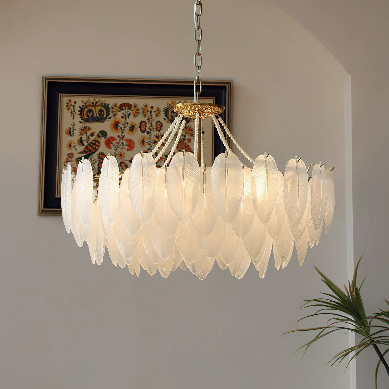 Modern feathered glass chandelier right front view with bright white glass shades and brass gold top fixture in arched hallway with wall tapestry and potted plants