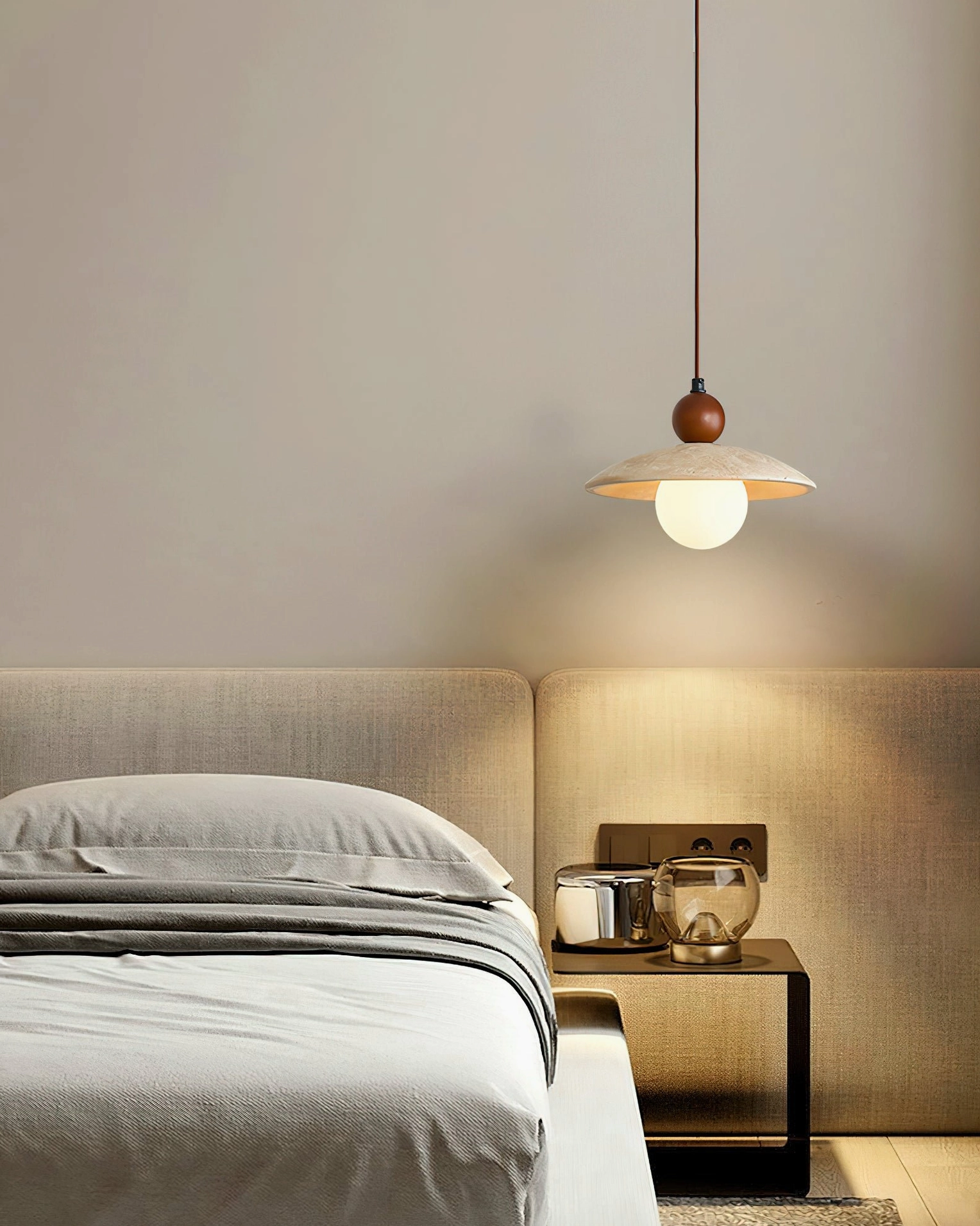 Ferox travertine pendant as bedside light fixture in modern neutral bedroom with fabric headboard