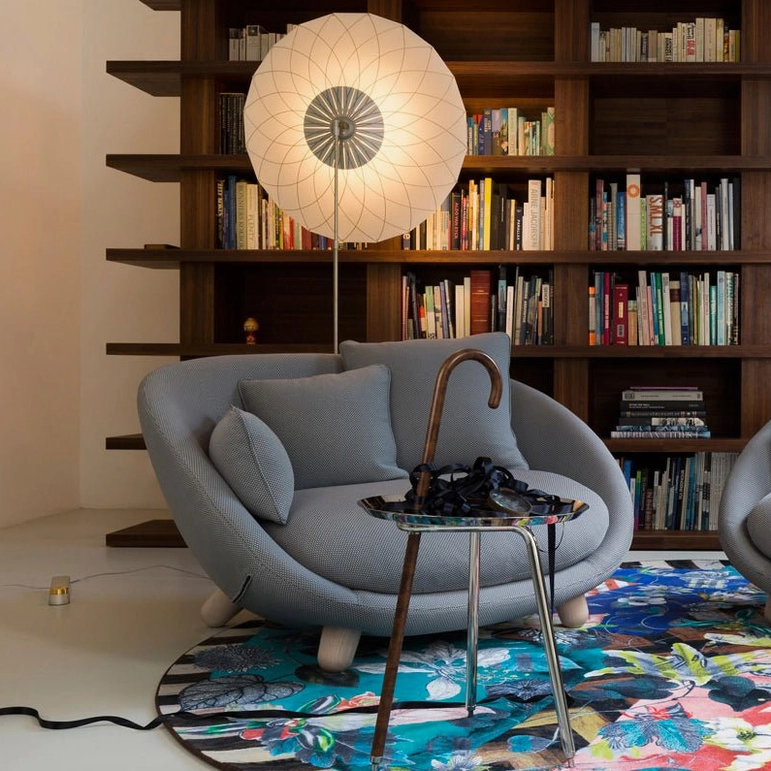 Filigree floor lamp in modern home library setting with warm ambient lighting illuminating bookshelf and reading area