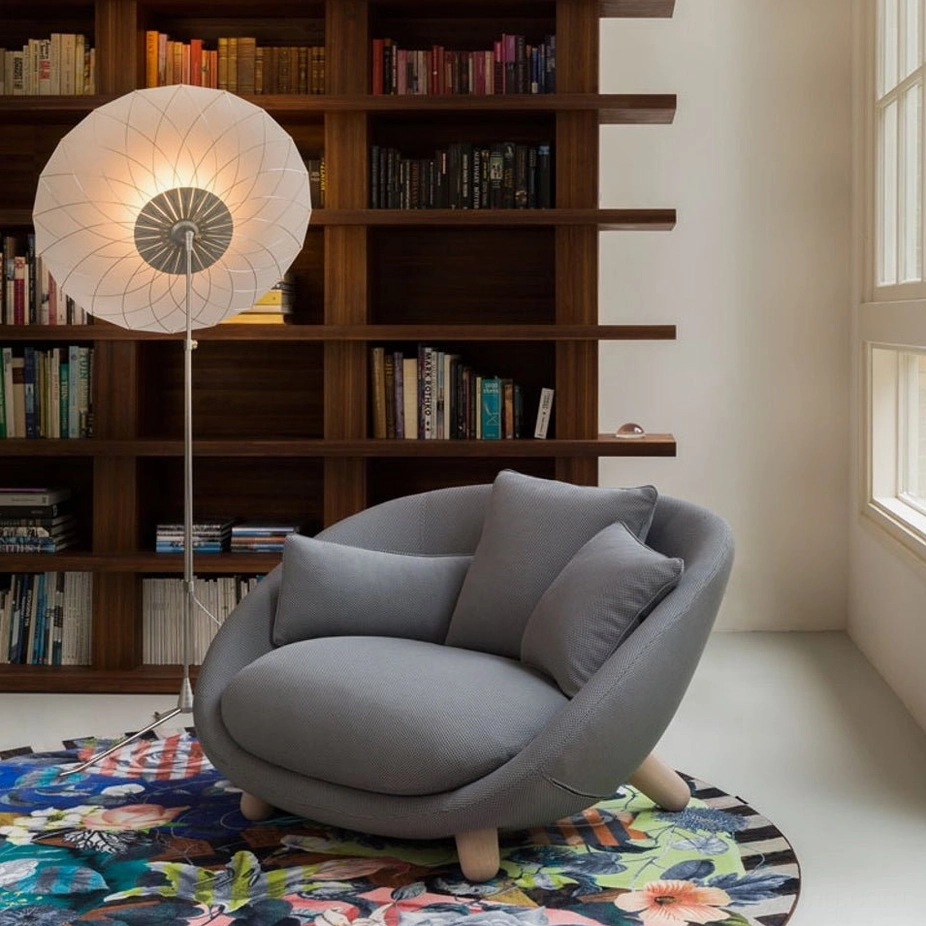 Filigree LED floor lamp positioned in cozy living room with gray lounge chair and dark wood bookshelves