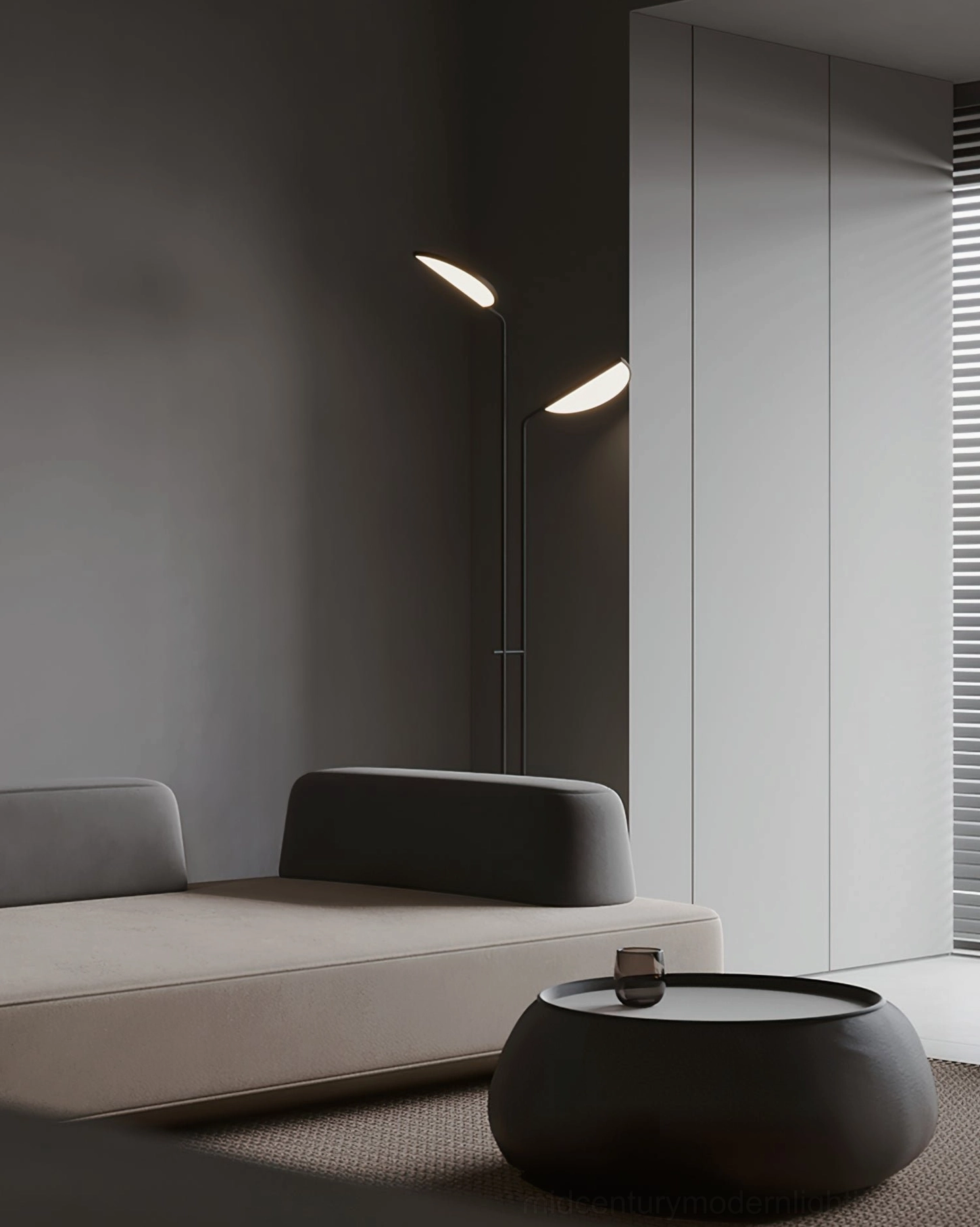 Black Filo floor lamp casting warm ambient light in dim contemporary living room with fabric seating - side interior view