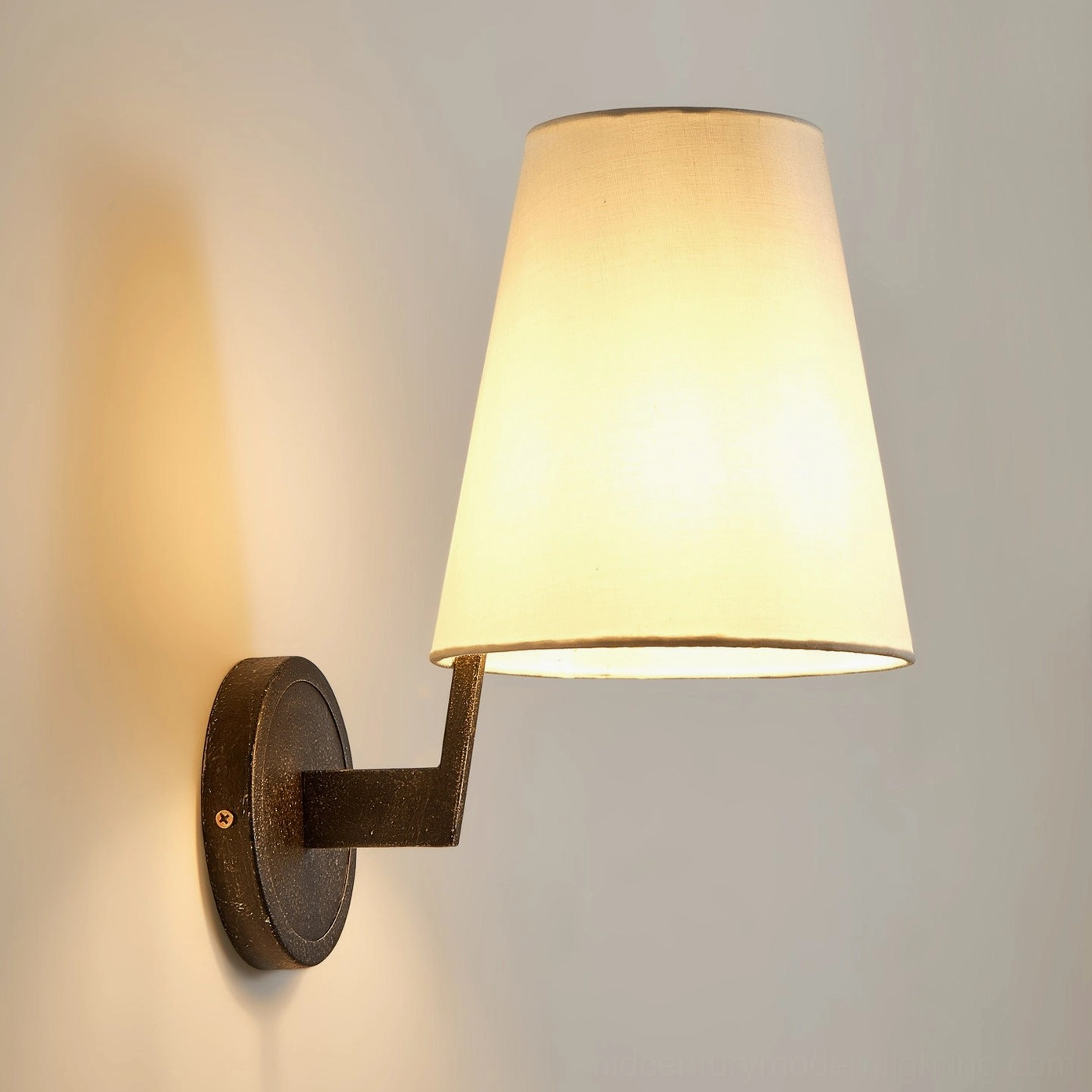 Finley wall sconce illuminated with warm ambient light, antique bronze finish, cozy reading nook lighting