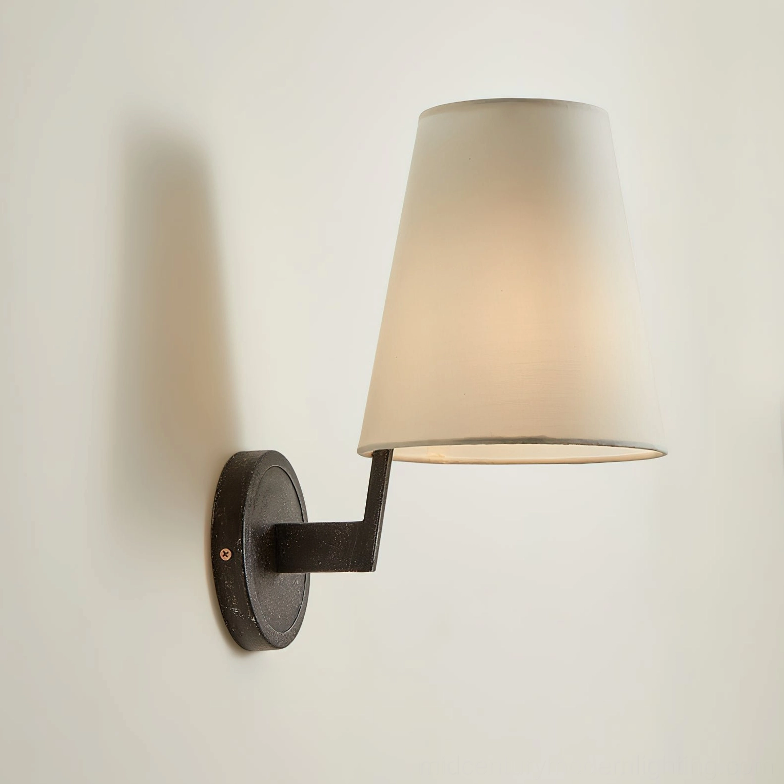Finley mid-century modern wall sconce with black metal mounting hardware, lit warm glow, side angle shot