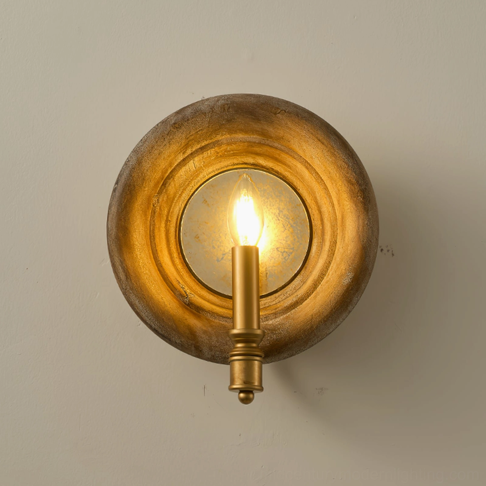 Finn wall sconce low-angle view with warm golden light glow on white wall, brass finish hardware