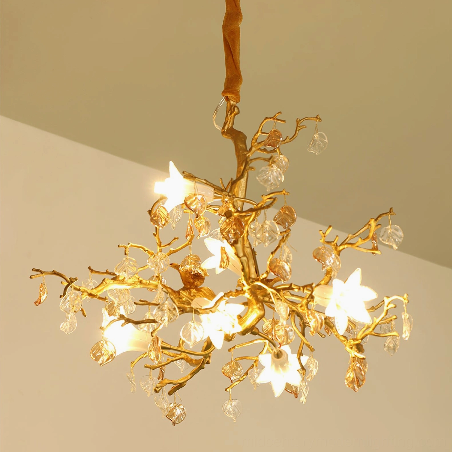 Bottom view of lit Fiori chandelier showing glowing flower lights, golden bird, and brass branch structure