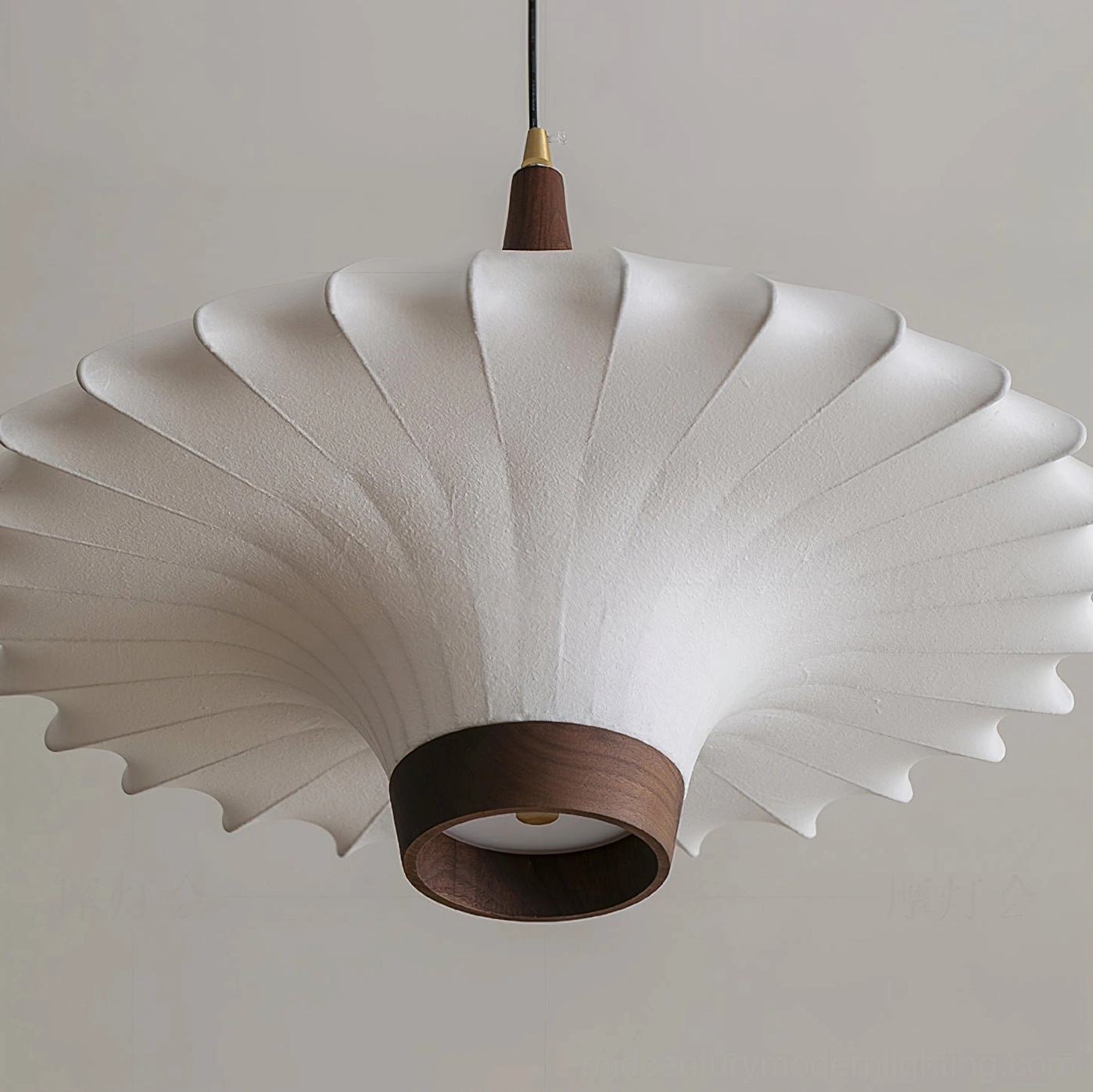 Flared pleated pendant lamp with soft fabric shade and dark wood trim ring, bottom close-up against white