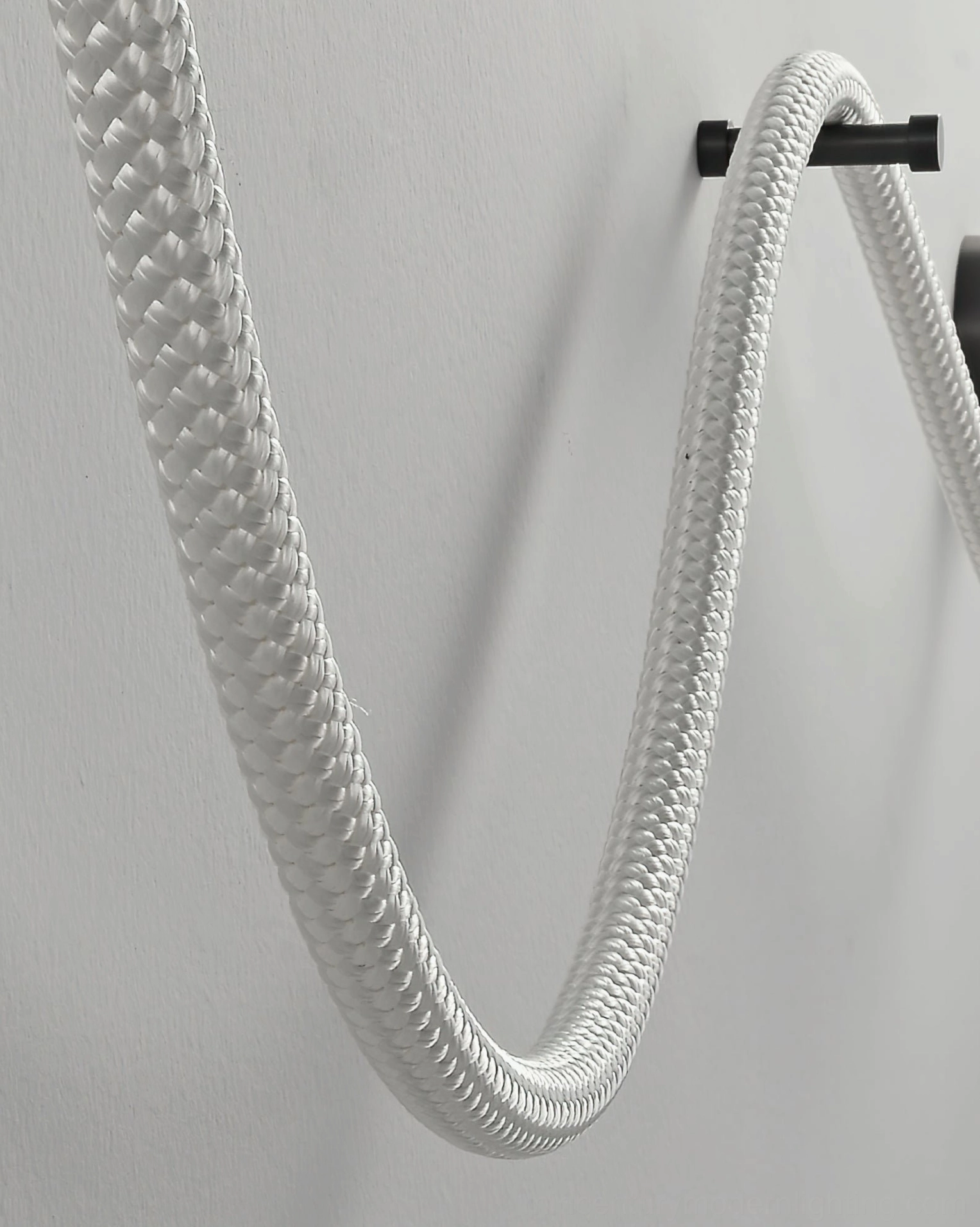 Unlit Flecto Tube braided rope wall lamp showcasing woven fiber exterior texture and black wall mounting clips on grey background