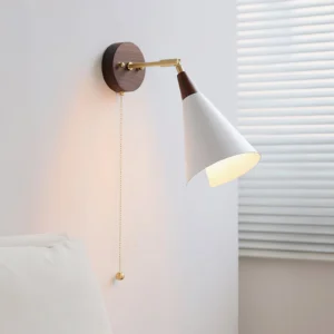 Fleka wall sconce mounted in bedroom, illuminated pull-chain switch detail, adjustable brass arm angled for reading light