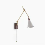 Fleka swing arm wall lamp studio view featuring brass articulated arms, walnut mounting plate, and white conical shade against white backdrop