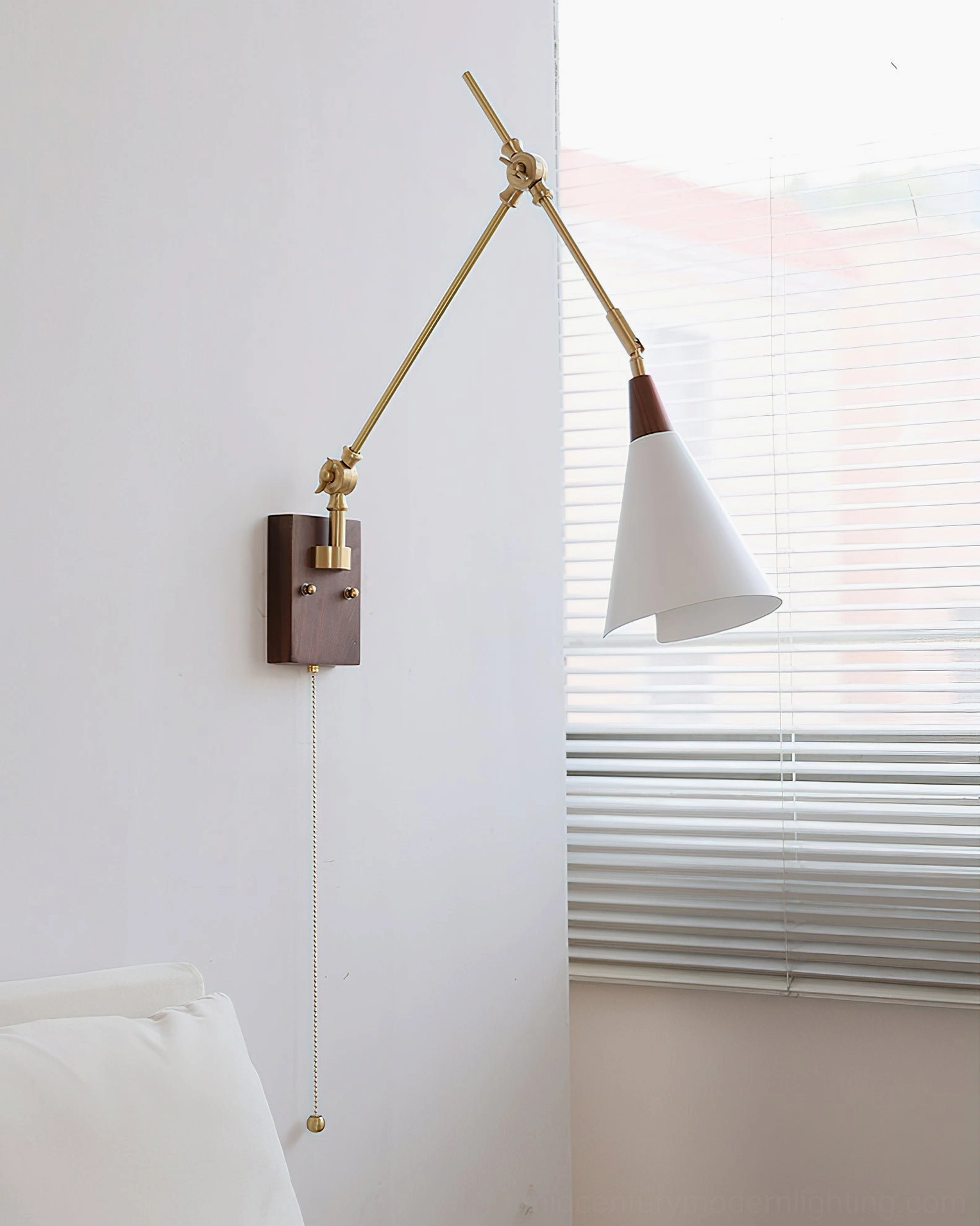 Adjustable swing arm wall sconce in bedroom showing articulated brass arms and unlit white shade with modern styling