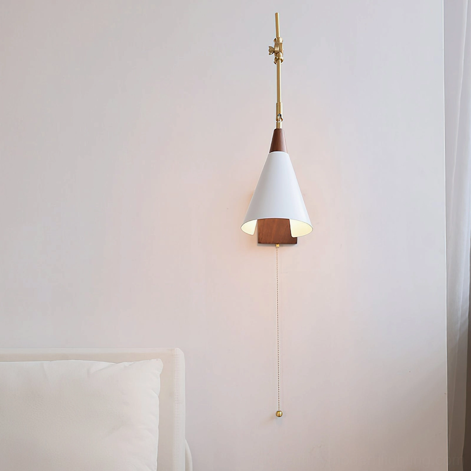 Mid-century modern wall sconce with brass stem and walnut base mounted in bedroom showing illuminated white shade and vertical mounting