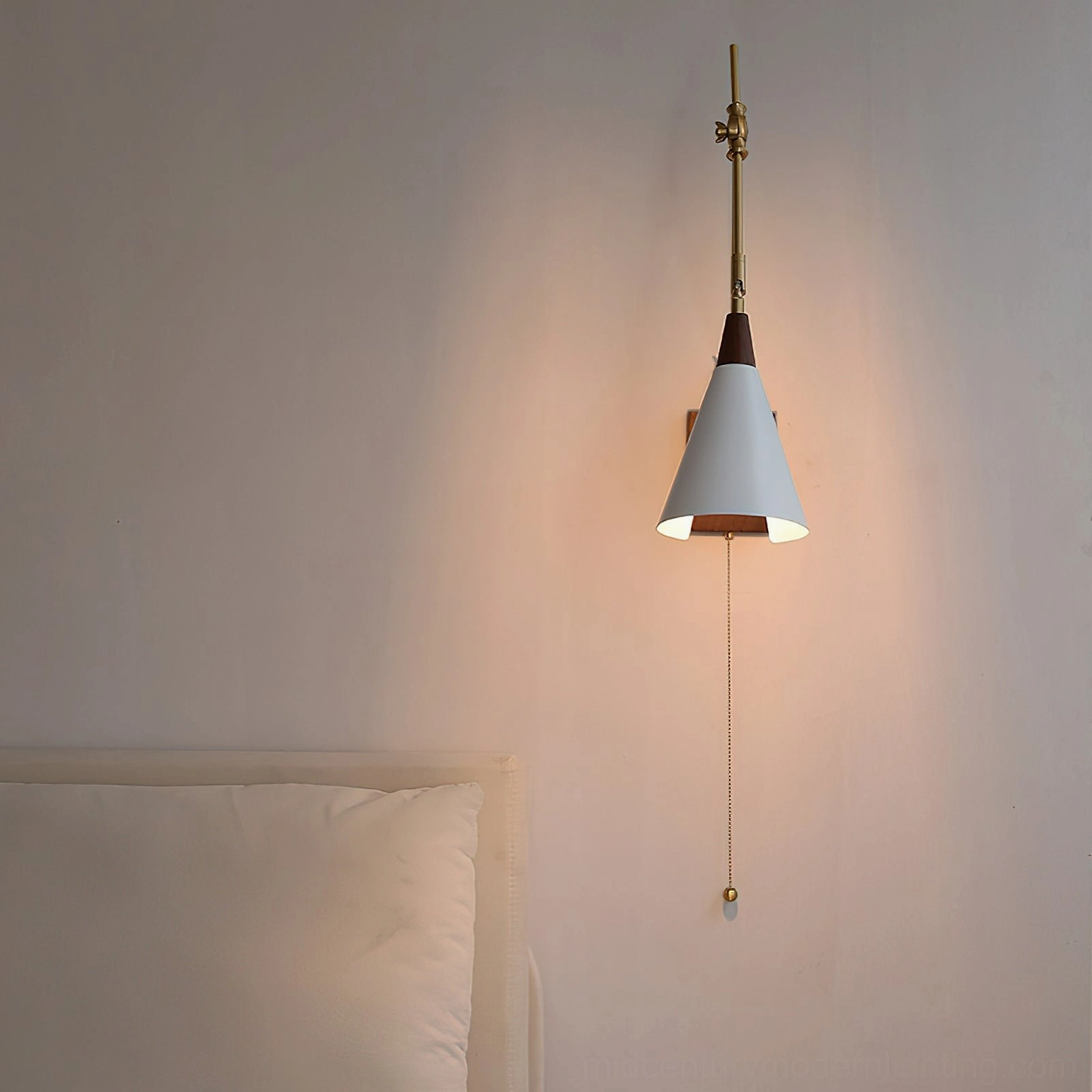 Illuminated Fleka wall lamp in bedroom corner showing warm glowing white shade and mid-century modern brass hardware