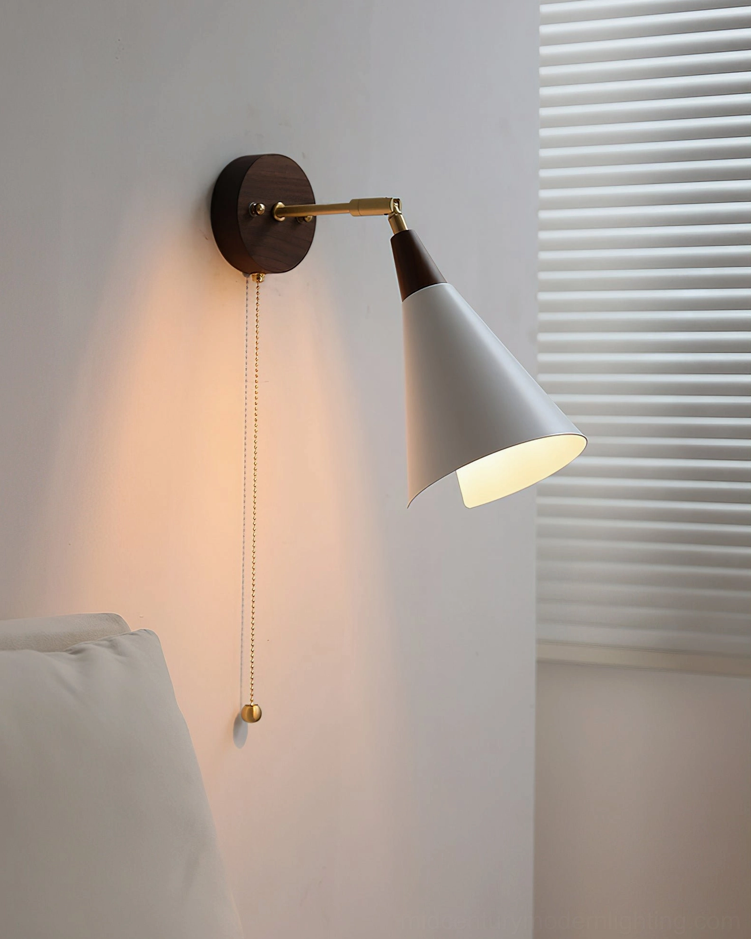 Fleka wall sconce with matte white shade mounted in bedroom, walnut wood backplate, side view with bedding background