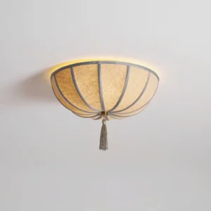 Fleur flush-mount ceiling light close-up detail showing natural woven beige fabric, sage green trim, and decorative gold tassel pendant