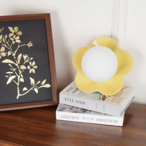 Yellow flower sconce on wooden side table with decorative books and framed artwork, styled interior shot