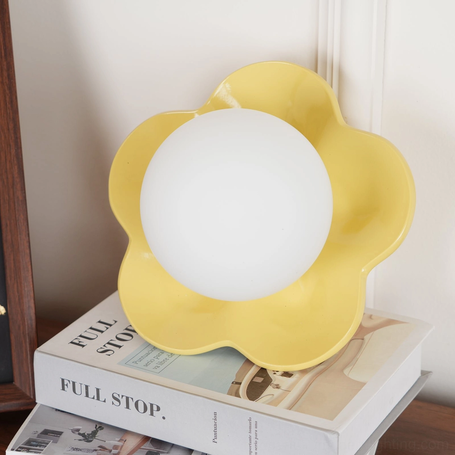 Oversized yellow flower wall sconce on wooden table with stacked decorative elements