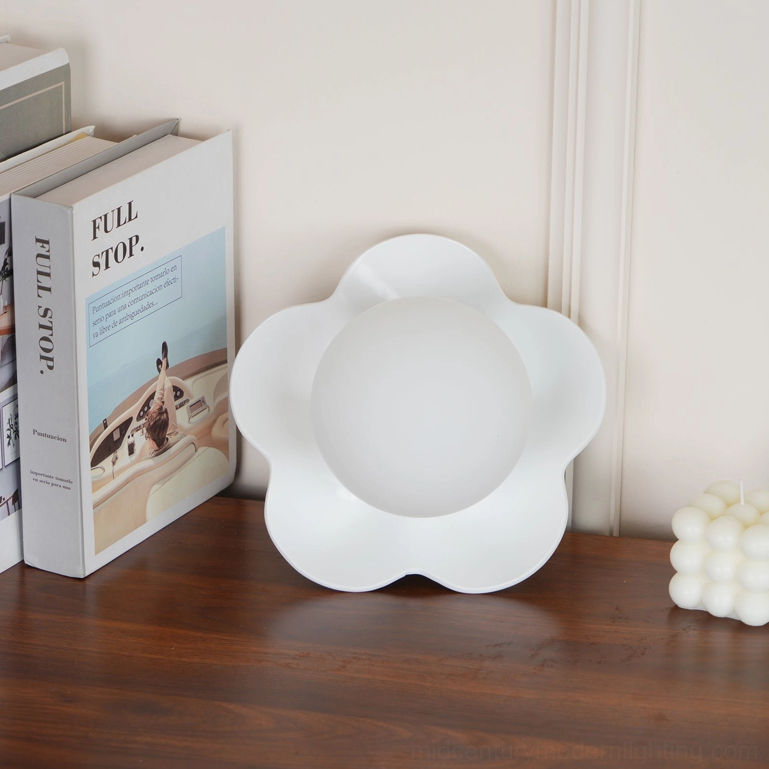Pure white resin flower wall lamp on wooden table with candle and book decor arrangement