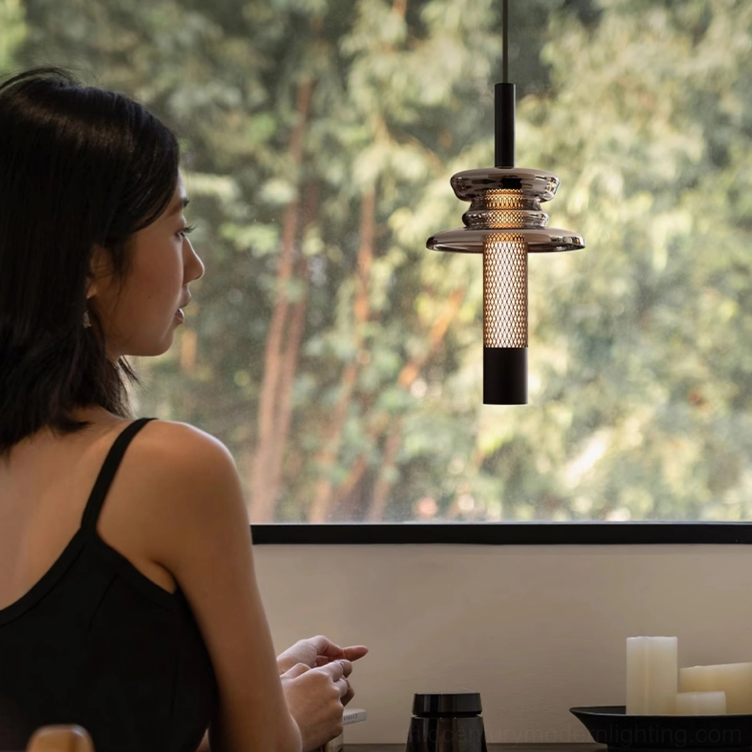 Float glass pendant light showing perforated metal cylinder and smoke glass layers in interior setting
