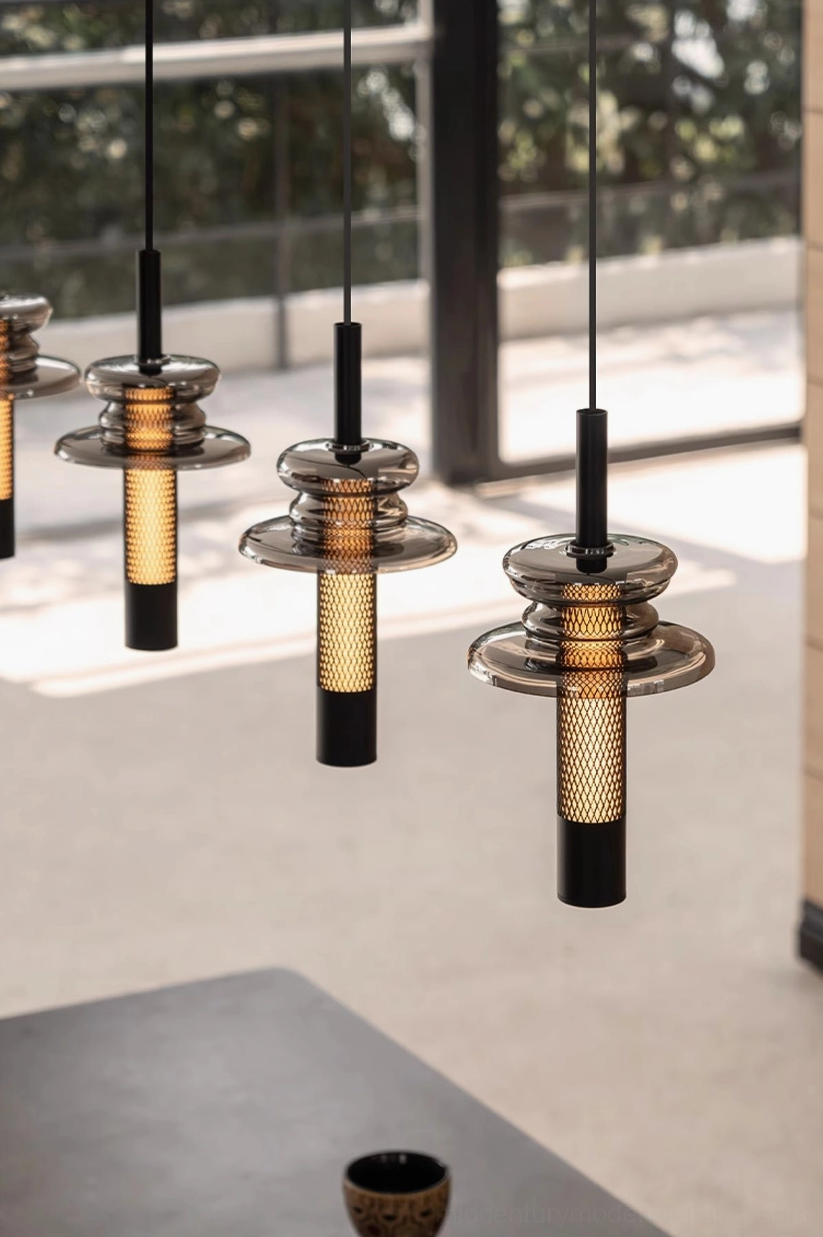 Close-up eye-level view of float pendant showing stacked metal-glass design with warm glowing light