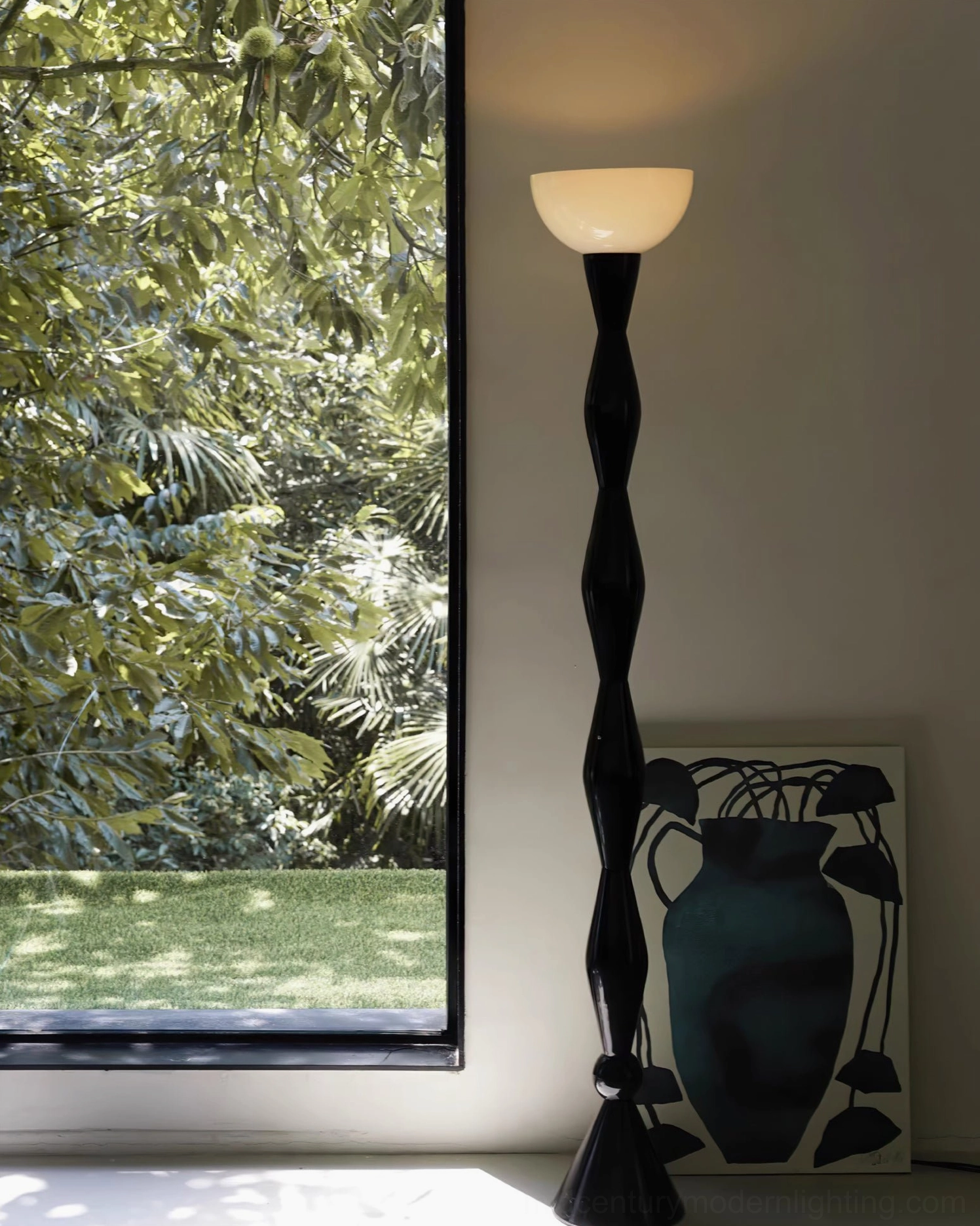 Black metal twisted torchiere lamp in room with garden view glass doors, natural minimalist home style