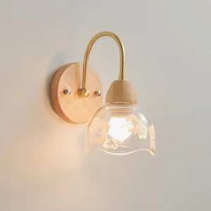 Close-up of etched floral glass shade on modern wall lamp, showcasing botanical pattern details