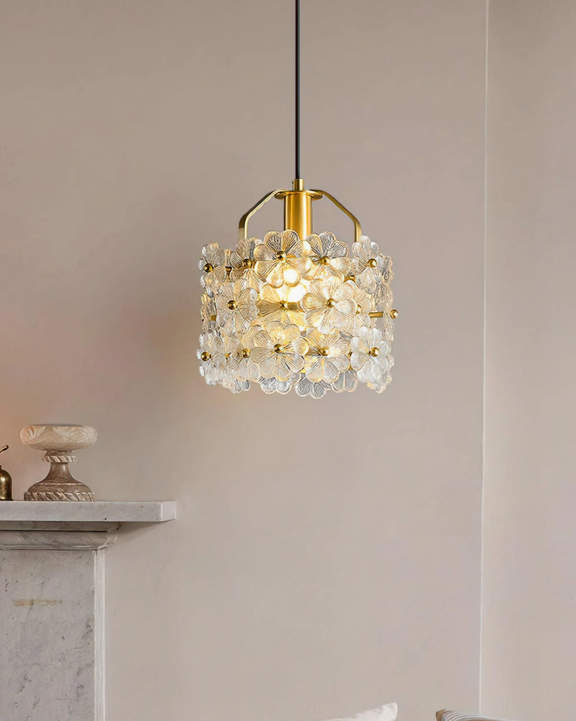 Brass glass flower pendant suspended above marble mantelpiece in warm neutral living room setting