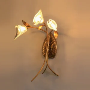 Brass Florentine wall lamp lit with warm amber light in residential interior setting